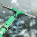 An Unger ErgoTec SwivelLoc green squeegee cleaning a window.