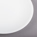 A Libbey alpine white porcelain coupe plate with a white rim on a gray surface.