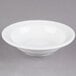 A Libbey alpine white porcelain fruit bowl with a rim on a gray surface.