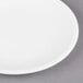 A Libbey Alpine White Porcelain Coupe Plate with a white rim on a gray surface.