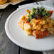 A Libbey Alpine White porcelain coupe plate with macaroni and cheese on it.