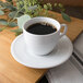 An alpine white porcelain saucer with a cup of coffee on it.