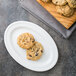 A Libbey Alpine white porcelain platter with oatmeal cookies on a table.