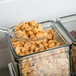 A spoon in a Cal-Mil aluminum display holding peanuts.