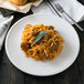 A Libbey Alpine White porcelain coupe plate with spaghetti, meatballs, and sage leaves.