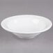 A Libbey Alpine White Porcelain Grapefruit Bowl with a rim on a gray surface.