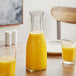 A table with a glass carafe and glasses of orange juice.