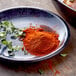 A plate with a pile of red powder and leaves.