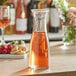 An Acopa glass carafe filled with wine on a table.