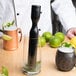A person using a Franmara heavy weight muddler to muddle mint and lime in a glass.