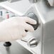 A person in white gloves adjusts the Centerline by Hobart meat slicer.