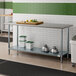 An Advance Tabco stainless steel work table with a galvanized undershelf in a kitchen.