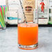 A glass of orange juice with a metal straw in an Arcoroc stirring glass.