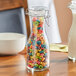 An Acopa glass carafe filled with colorful cereal on a hotel buffet table.