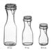 Three Acopa glass carafes with black resealable lids.