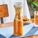 An Acopa glass carafe filled with orange liquid and fruit on a table.