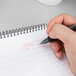 A hand writing on a TOPS Docket Gold spiral planner pad with a pen.