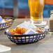 A Tablecraft black oval plastic basket filled with fried food on a table.