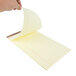 A hand holding a TOPS yellow lined legal pad.