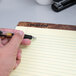 A hand holding a pen over a TOPS wide ruled legal pad.