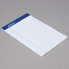 An Ampad white notepad with blue lines on the paper.