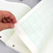 A hand holding a green sheet of Quadrille paper.