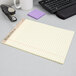 A TOPS Second Nature wide ruled legal pad on a desk with a stapler.