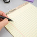 A person using a TOPS Second Nature legal pad to write with a pen.