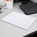 A brown Ampad wirebound planner pad on a white desk with pens in a mug.