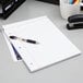 An Ampad wide ruled white 3-hole punched writing pad with a pen on it.