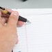 A hand holding a pen writing on wide ruled lined paper.