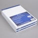 A stack of white Ampad wide-ruled writing pads with blue and white writing on them.