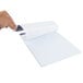 A hand holding a white Ampad Quadrille ruled writing pad over a piece of paper.