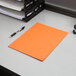 An orange Oxford 2-pocket paper folder on a desk.