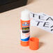 An orange tube of Elmer's Clear School Glue Stick on a table.