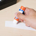 A hand holding an Elmer's clear glue stick.