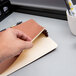 A hand holding a brown Pendaflex legal size file pocket.