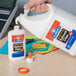 A close-up of a hand holding a white jug of Elmer's white liquid school glue.