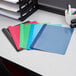 A stack of Oxford clear front report covers in assorted colors on a desk.