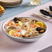An aluminum tray of seafood with lemon wedges and shrimp on a table.