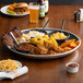 A Choice aluminum tray with food including corn on the cob and coleslaw.