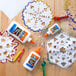 A white bottle of Elmer's white liquid school glue on a table with paper snowflakes.