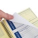 A hand using an Adams Write 'n Stick carbonless phone message pad to write a message.