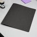 A black Oxford report cover with fasteners on a white surface.