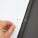 A hand using a black Oxford report cover with paper clips.