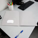 A gray Oxford 2-pocket paper folder on a desk with paper and pens.