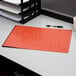 An Oxford red pressboard report cover on a desk next to a cup of coffee.