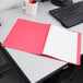 A red Oxford report cover on a desk with lined paper and a black keyboard.