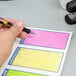 A hand holding a pen writing a message on an Adams Wire Bound Phone Message Book.