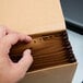 A hand opening a brown box of Pendaflex A-Z indexed file folders.